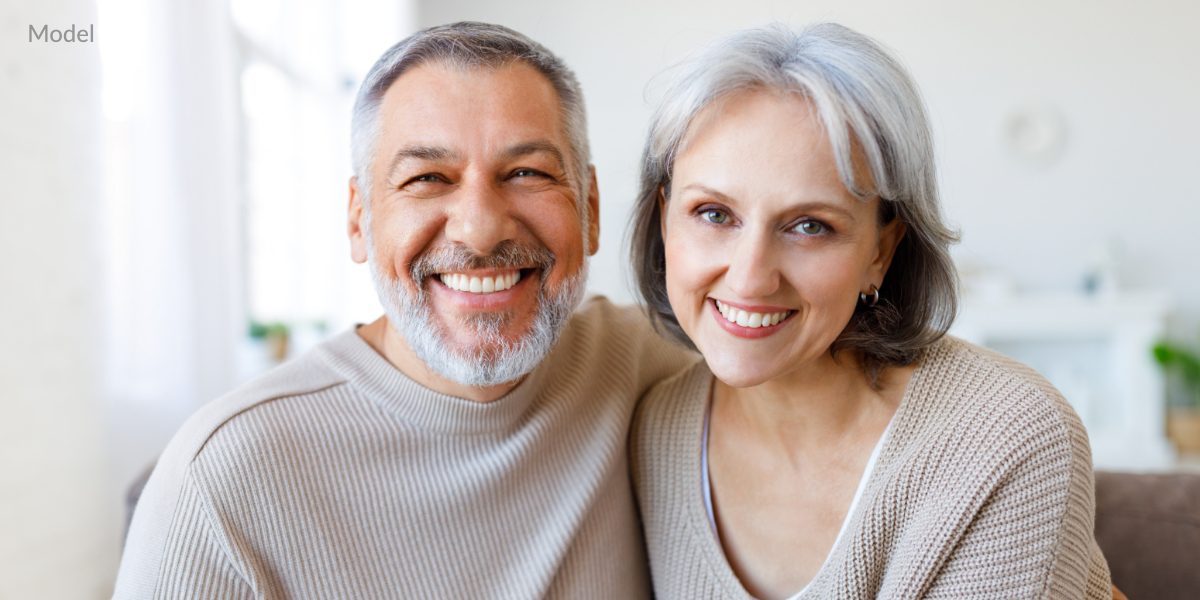 Smiling models demonstrate the potential results of dental implants.